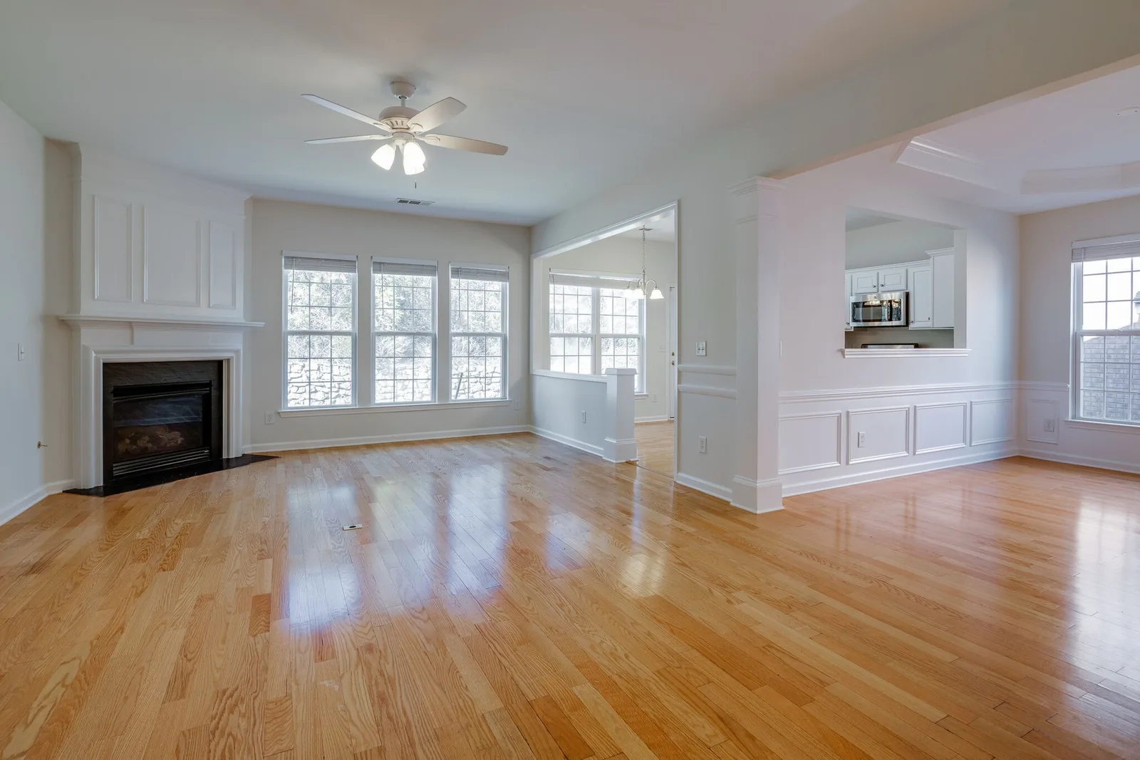 Sunlit great room with hardwood floors opening through to the dining area and kitchen